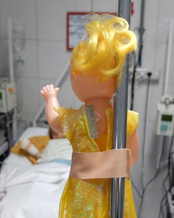 There was a doll with blonde hair and a yellow dress above the bed, looking at her owner – Amina.