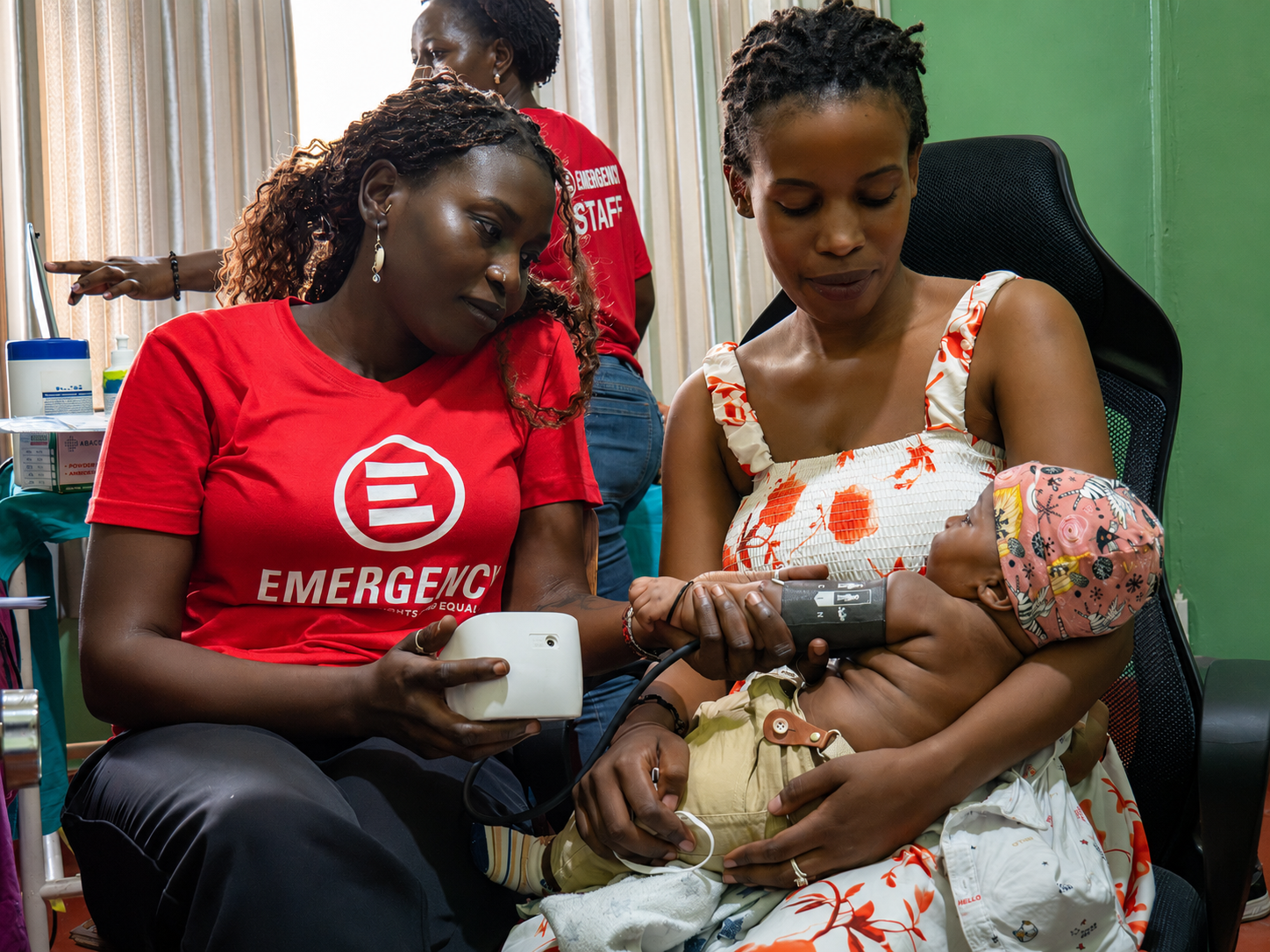 Mom holding baby while medical staff performs check up